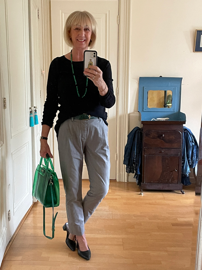 Grey trousers with black jumper and green accessories