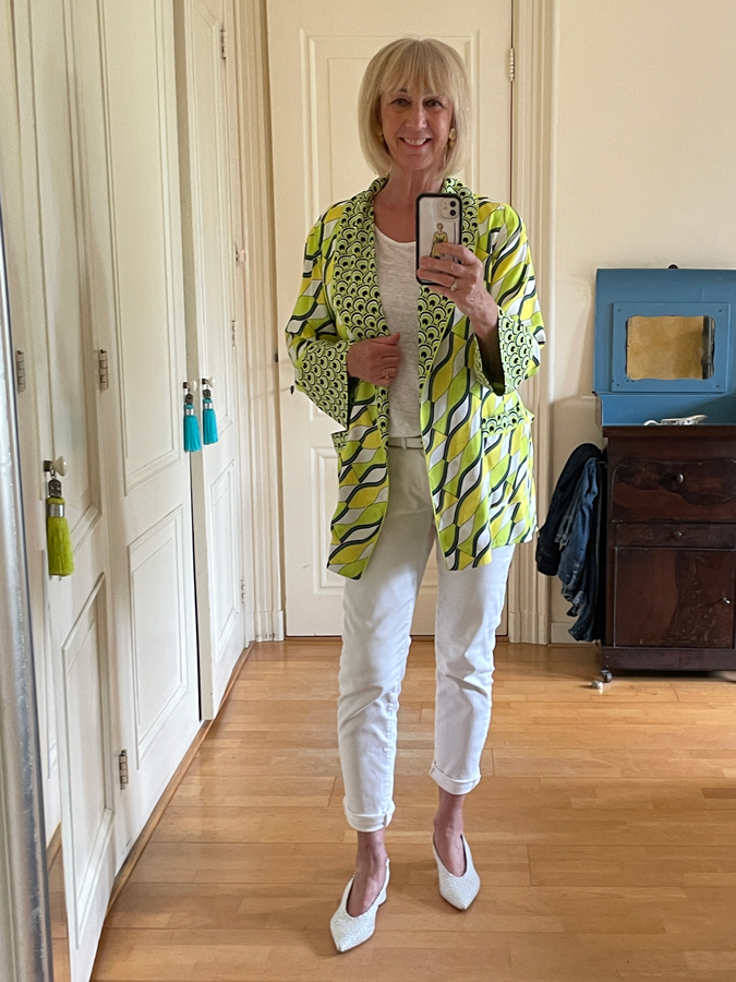 Outfit with lime coloured patterned jacket on a column of white