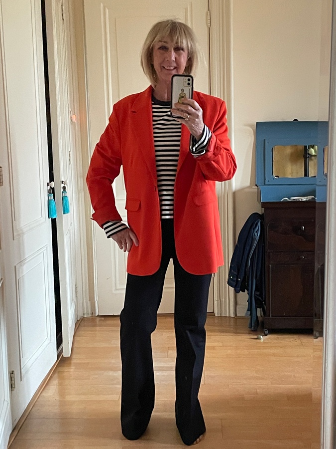Flared black trousers with an orange blazer and a striped shirt