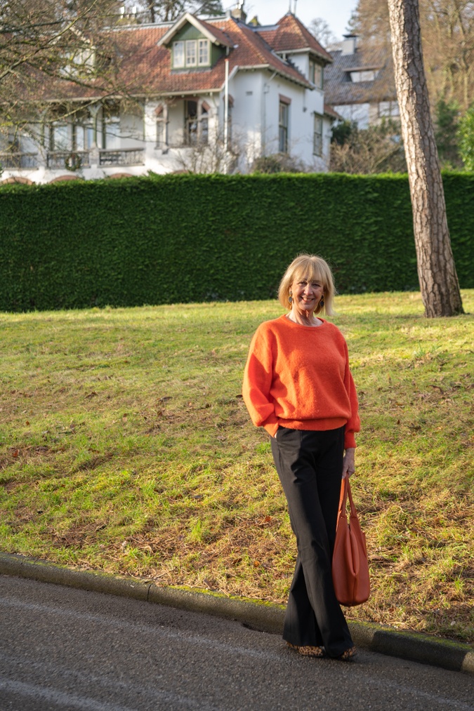 Flared black trousers with an orange jumper