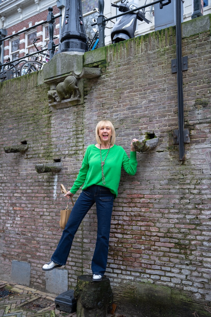 green jumper with flared jeans and trainers