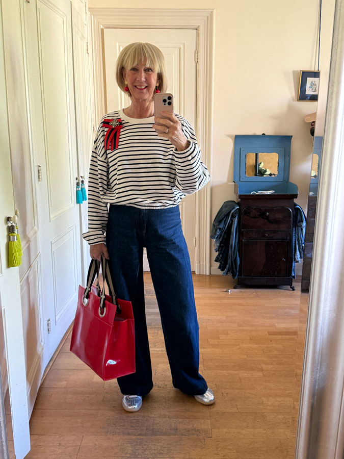 Jeans with blue and white striped sweater and silver trainers.