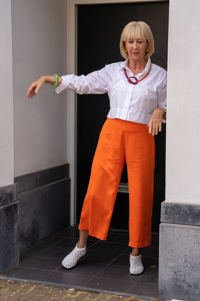 White cropped blouse jacket with orange trousers