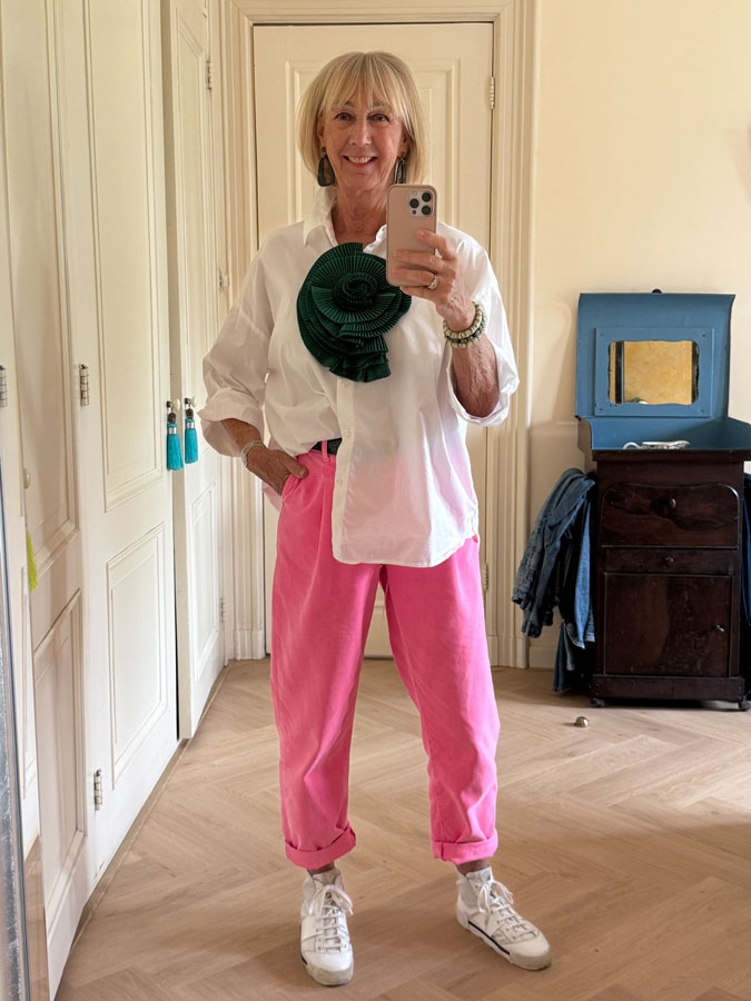 Outfit with pink trousers and a green rosette brooch